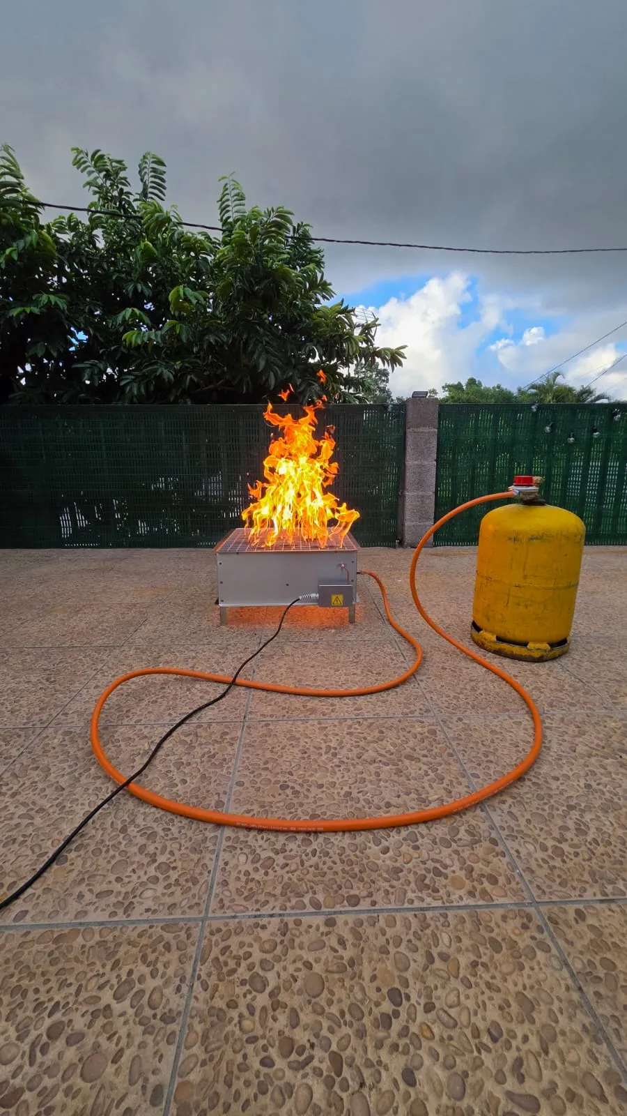 Bac à feu GF 42 en fonctionnement, flammes hautes et bouteille de gaz reliée par tuyau